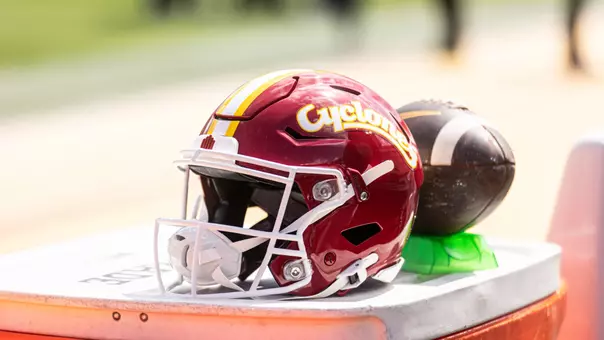 Iowa State cardinal helmet next to football.