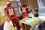 Deonte Mack (55) and Dre Muhammad visit with a patient at Riley Hospital.