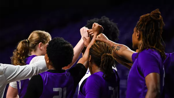 JMU women's basketball players put their hands in during a huddle at practice.