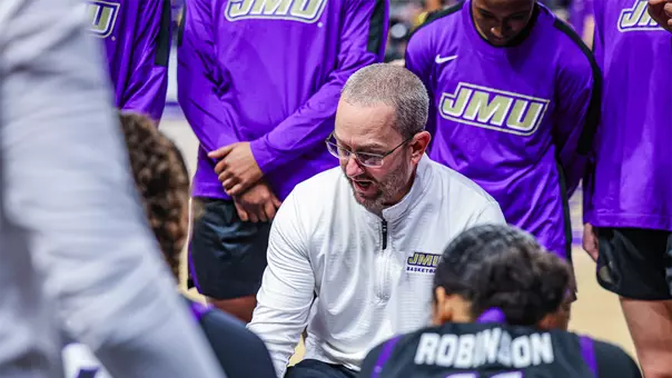 Head Coach Sean O'Regan talking to his team in a huddle during a timeout.
