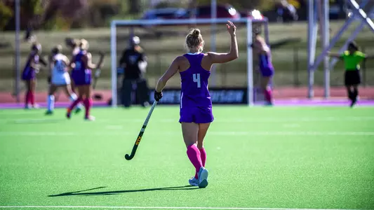 Lilly Turner with her back to the camera, motioning to her teammates following a successful defensive penalty corner versus Massachusetts at the other end of the field at the JMU Field Hockey Complaex