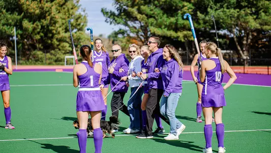 Julie Narleski accompanied by family walking through tunnel of teammates with their sticks raised during Senior Day ceremony before playing Ohio at the JMU Field Hockey Complex