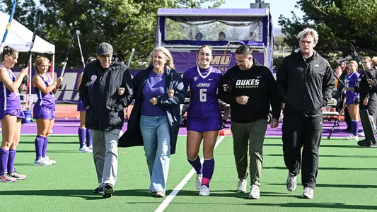 Maddie Tierney walking with family during Senior Ceremony before playing Ohio at the JMU Field Hockey Complex