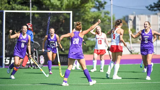 Skyler Brown raising her first in the air as teammates run to to celebrate goal with her against Ball State at the JMU Field Hockey Complex