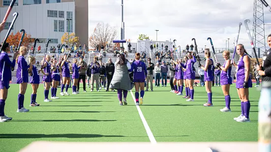 Skyler Brown and her mother with back to the camera walking across midfield line during Senior Day ceremony at the JMU Field Hockey Complex