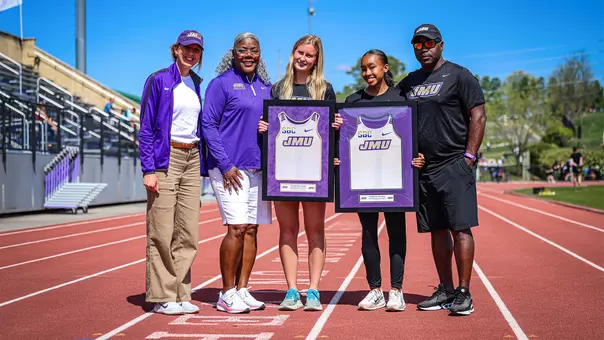 Track & field coaches posing with seniors Kadence Wilson and Faithe Ketchum during Senior Day Recognition at Sentara Park