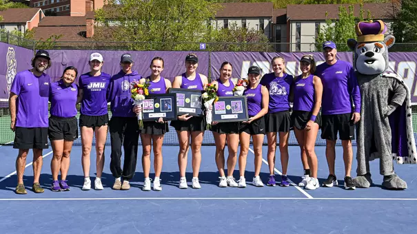 JMU's three seniors, Daria Munteanu, Reka Matko and Sophie Williams, take a pre-match photo with the entire team, coaches and Duke Dog.