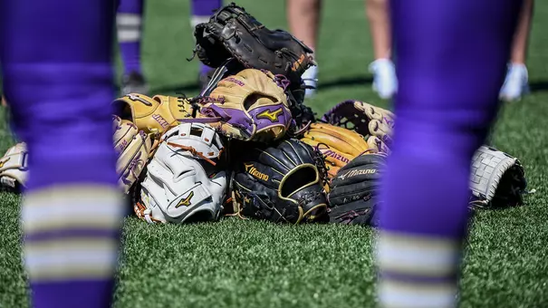 James Madison Softball team gathers around their softball gloves pregame.