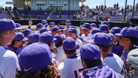 JMU baseball players huddling together after winning a series against Marshall.