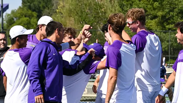 JMU men's tennis huddles before its match vs. George Mason in spring 2026.