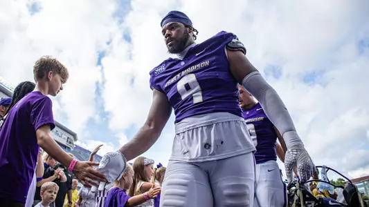 Kei'Trone Simpson high fives a fan following JMU's win over Liberty