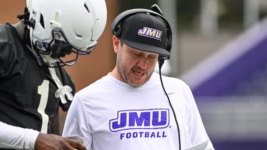 Cam Aiken coaches JC Evans during a JMU football practice