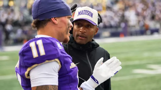 RJ Fleming coaches a wideout during a JMU football games