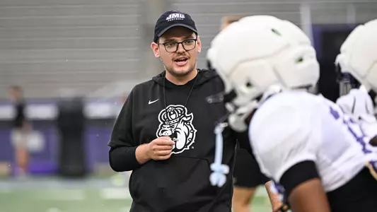 Alex Loytyy instructs the team during a JMU football practice
