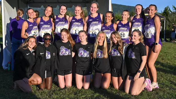 JMU Cross Country team posing in front of a tent at the New Market Battlefield.