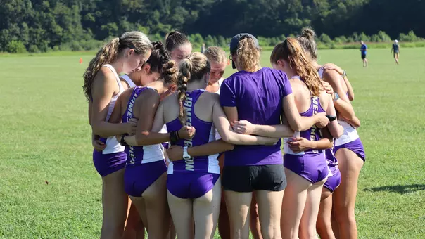 Cross country team huddles together before racing at Pole Green Park.