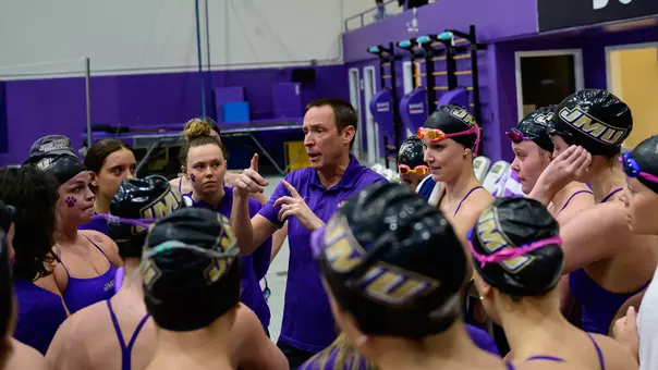 JMU Swim and Dive huddles with coach Dane Pedersen before its meet against Navy