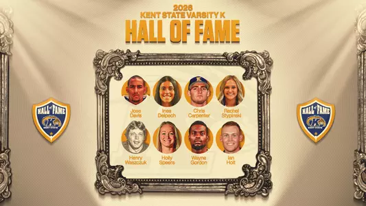 Graphic announcing the 2026 Kent State Varsity K Hall of Fame class. An ornate antique silver frame at center holds eight circular headshots in two rows of four, each with the honoree’s name beneath: Jose Davis, Ines Delpech, Chris Carpenter, Rachel Stypinski, Henry Waszczuk, Holly Speers, Wayne Gordon and Ian Holt. Waszczuk’s photo is black and white. Carpenter wears a navy Kent State baseball cap. “2026 Kent State Varsity K Hall of Fame” appears in gold lettering above the frame, and a navy and gold Kent State Hall of Fame shield logo sits on each side, all against a cream and tan draped-fabric background.