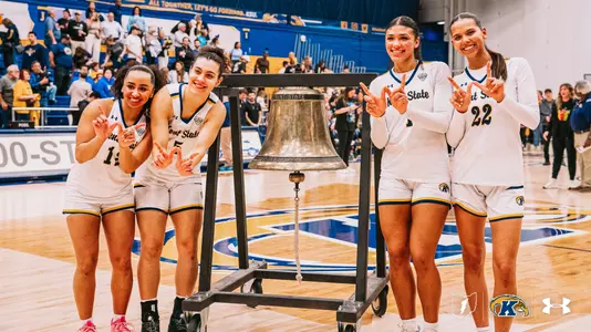 Women's basketball seniors Dionna Gray, Bianca Juzzo, Tatiana Thomas and Joy Bergstrom pose with the Victory Bell