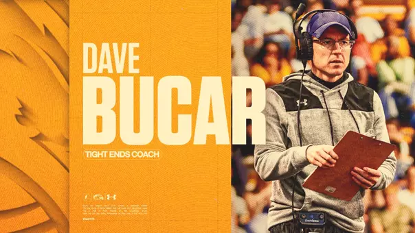 Coaching announcement graphic featuring 'Dave Bucar – Tight Ends Coach' in large cream and gold text on an orange and gold background at left, alongside an action photo of Bucar on the sideline wearing a headset, glasses, and gray Under Armour hoodie while holding a clipboard, with a crowd visible behind him and the Kent State lightning bolt, Golden Flashes, and Under Armour logos at lower left.