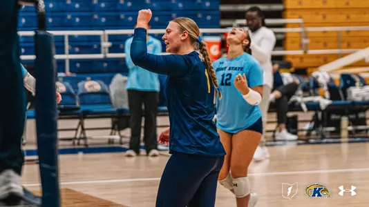 Two Kent State volleyball players celebrate a point, with No. 1 Maggie Kachmarik pumping her fist in the foreground and No. 12 Catie Patterson raising her arms in excitement behind her on the court at the M.A.C. Center.