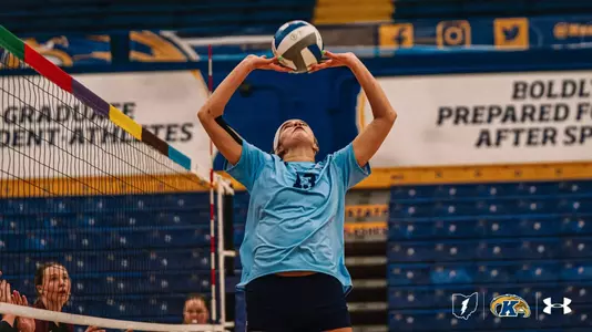 Kent State volleyball player Jordyn Anderson, wearing No. 13, sets the ball near the net during a match at the M.A.C. Center, arms extended overhead with eyes tracking the ball.