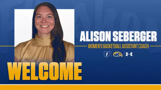A Kent State Athletics welcome graphic announcing Alison Seberger as Women's Basketball Assistant Coach. The blue and gold graphic features a headshot of Seberger, a woman with long dark hair wearing a gold top, smiling at the camera. The word "WELCOME" appears in large gold block letters across the bottom left. Her name is displayed in large white bold text on the right side, with "WOMEN'S BASKETBALL ASSISTANT COACH" in gold text beneath it. The Kent State Athletics logo, Ohio state outline icon, and Under Armour wordmark appear in the lower right.