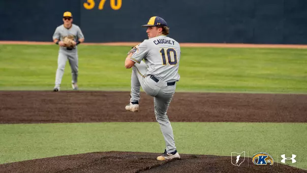 Kent State Golden Flashes pitcher Ciaran Caughey, wearing No. 10 in a gray Under Armour jersey and gray pants, winds up in a high leg kick on the mound, with a teammate positioned in the infield behind him and the outfield wall with the distance marker '370' visible in the background.