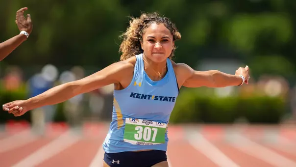 Kent State sprinter Amryne Chilton (bib 307) leans across the finish line with arms spread wide during the MAC Outdoor Track and Field Championships.