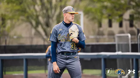 Kent State Golden Flashes pitcher wearing No. 37 walks on the field in a gray 'Kent State Golden Flashes' Under Armour jersey with navy sleeves, gray pants, and a gray gold-brimmed cap, holding his glove, with a teammate and the outfield fence visible in the background.