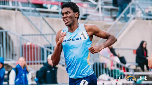 Kent State track and field athlete Gabiel Wise, wearing a light blue Under Armour uniform with "Kent State" across the chest and bib number 1, sprints during a race at the OSU Invitational. The Kent State Athletics logo and Under Armour wordmark appear in the bottom right corner.