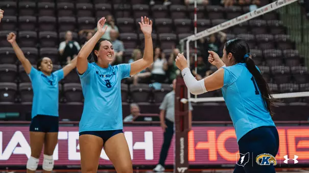 Kent State volleyball players celebrate on the court in front of a mostly empty arena during a match against Virginia Tech.