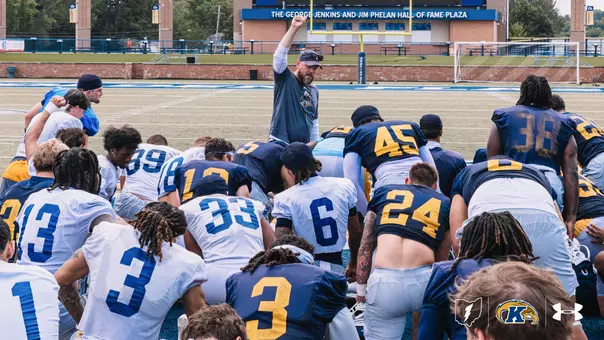 the Kent State football team huddled up around head coach mark carney