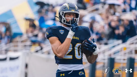 Kent State Golden Flashes college football player wearing jersey number 20 and a dark blue helmet featuring gold lightning bolt decals and a MAC conference logo on the jersey.