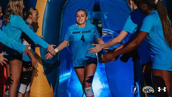 ent State volleyball player No. 4 runs through a tunnel of teammates' outstretched hands during pregame introductions, smiling as she high-fives players lined up on either side under blue lighting.