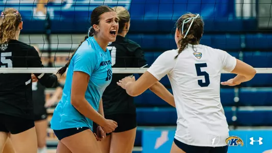Kent State player (#18) celebrates with a teammate (#5) at the net, fist clenched.