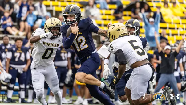 Action photo of a Kent State football player wearing number 12 running with the football past Wofford defenders during a game.