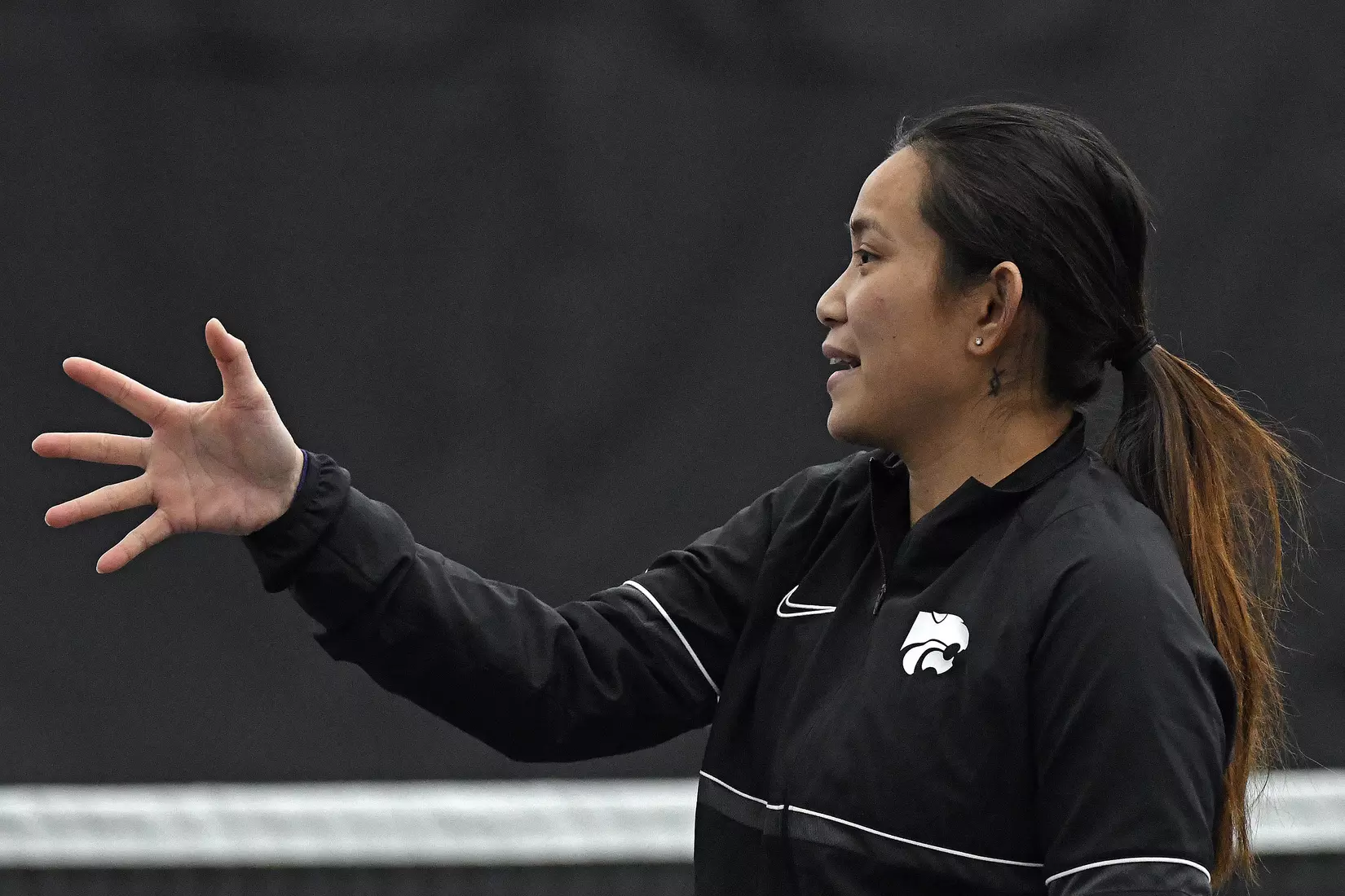 K-State’s coach Trang Huynh-McClain directs the Wildcats against Memphis at the Body First Indoor Tennis Center in Manhattan, Kansas on February 11, 2022.