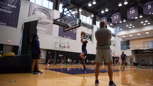 Coach Mittie watches Ayoka Lee shoot a layup at the Ice Family Basketball Center