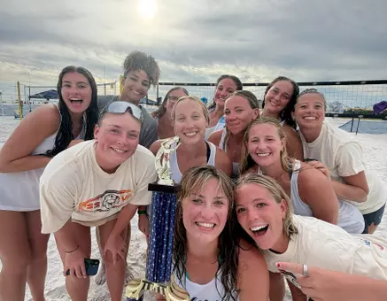 Women's beach volleyball celebration with trophy