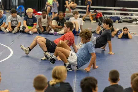 Wrestling campers crawl backwards during drill