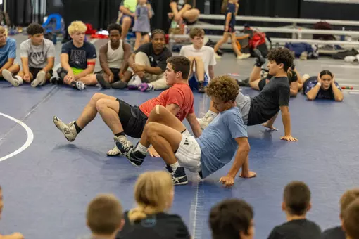 Wrestling campers crawl backwards during drill