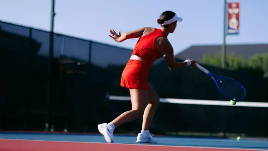 Women's Tennis photo from behind Murio Turchetto as he hits a forehand at a practice