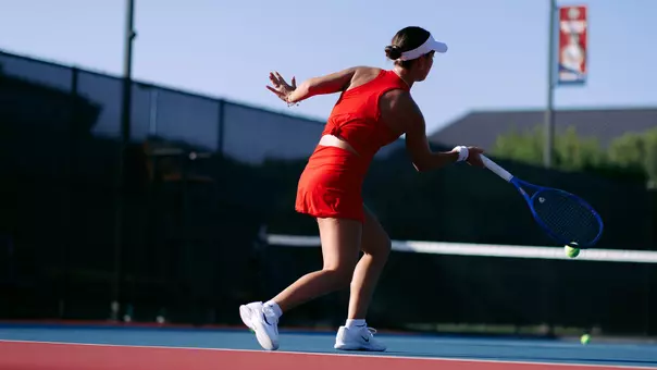 Women's Tennis photo from behind Murio Turchetto as he hits a forehand at a practice