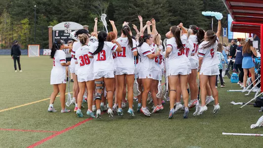 Women's Lacrosse Celebrates on the sideline in a game at the Liberty Lacrosse Field