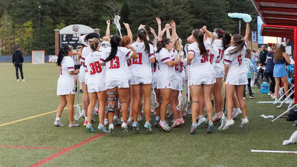 Women's Lacrosse Celebrates on the sideline in a game at the Liberty Lacrosse Field