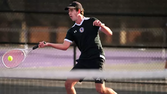 Oskar Szymczak swings a tennis racquet
