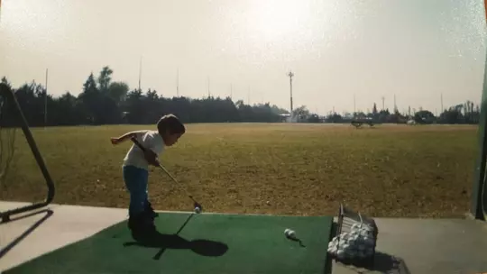 Child (Diego Prone) hitting golf balls on driving range