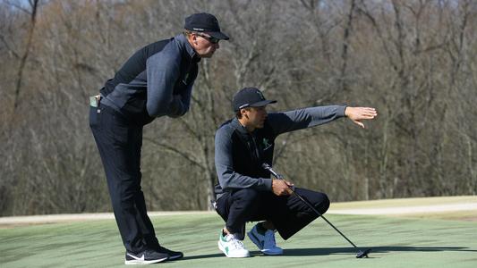 Head coach Brad Stracke helping Vicente Marzilio assess a putt at Trinity Forest