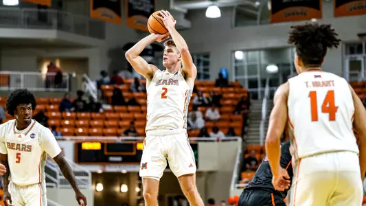 Mercer men's basketball player wearing a white jersey in the air shooting the basketball